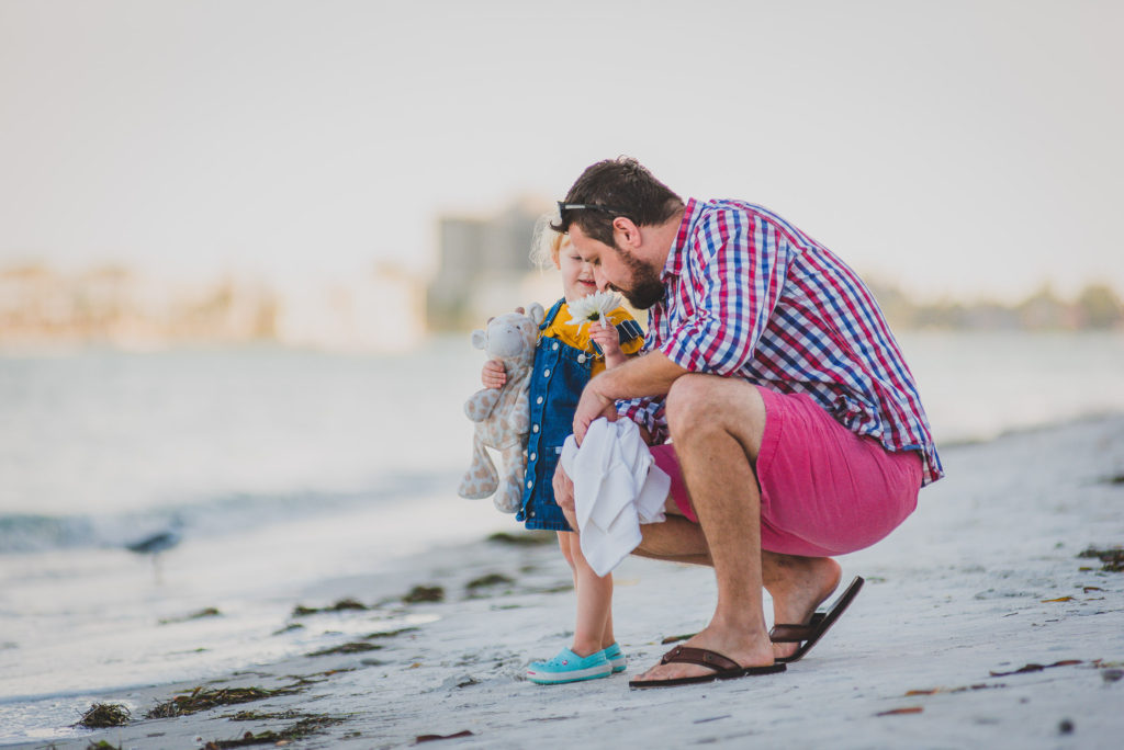 father and daughter having fun at the beach during sunset