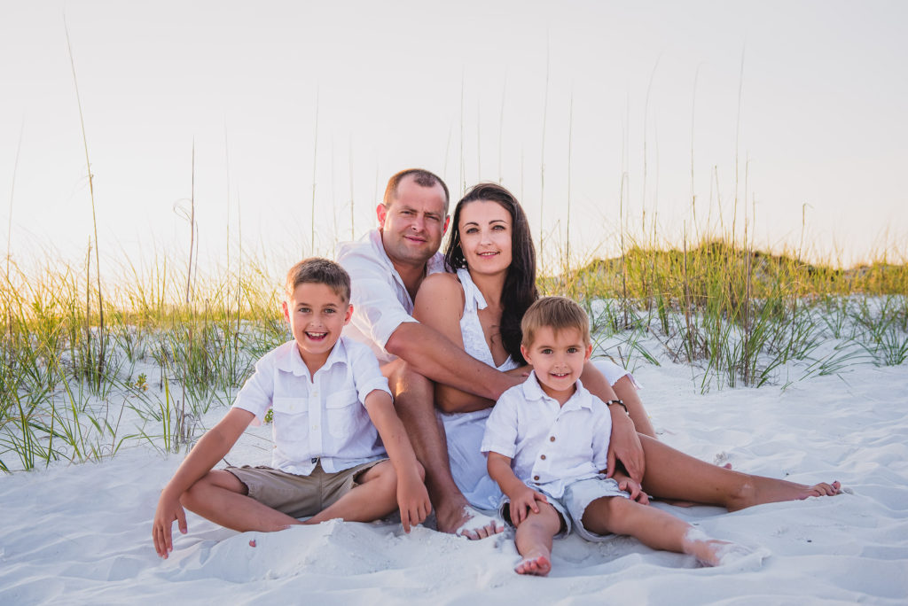 family of four siting at white sand of Florida beach