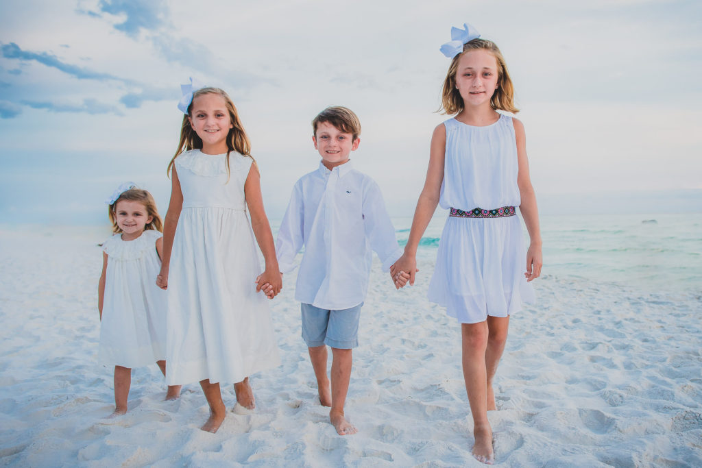 four kids wearing white clothes walking in white sand Maria Anna Island