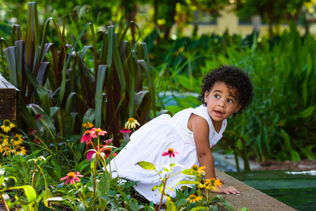 beautiful girl with white dress playing with water in the flower garden