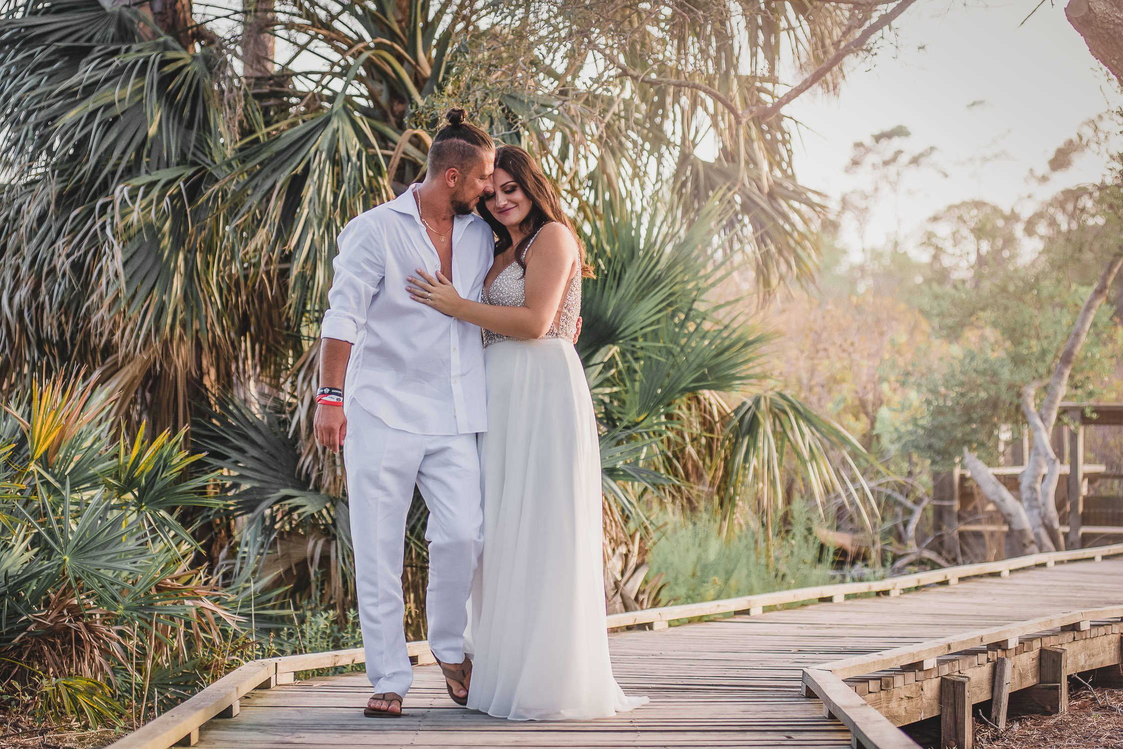 bride and groom walking holding each other on a deck with florida palms garden