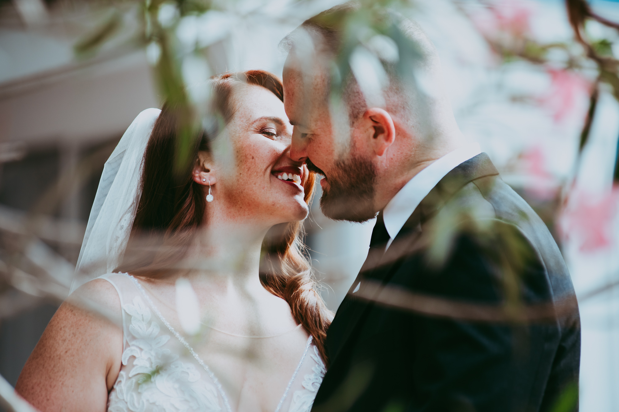 bride and groom smiling before the kiss behind a flower tree