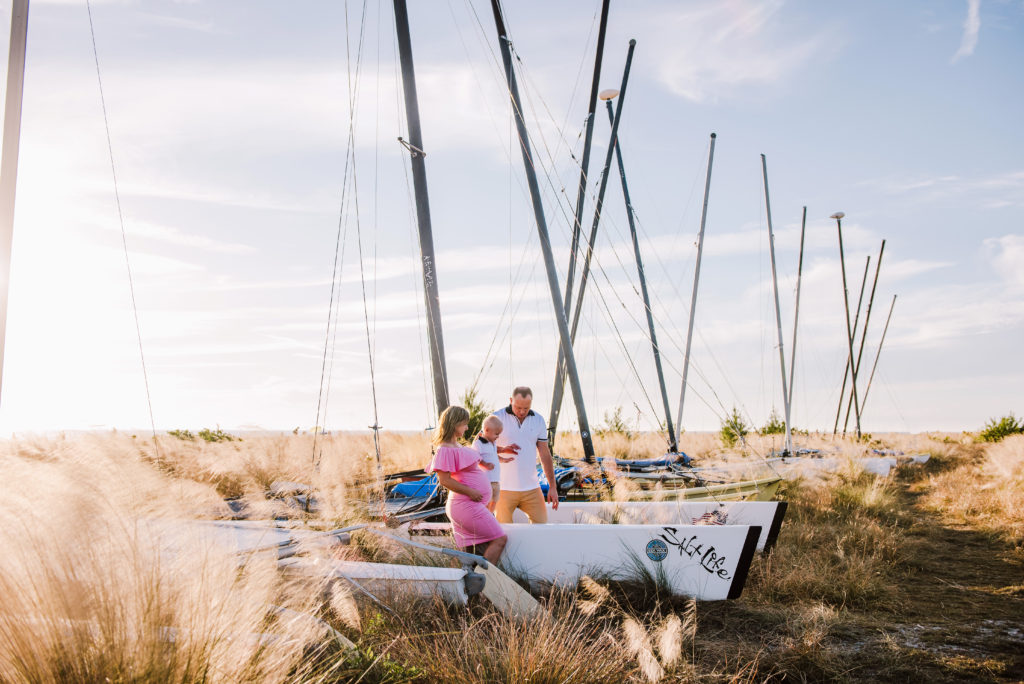 Candid image of Family during sunset in the tall grass with sailing boat at Siesta Key Beach