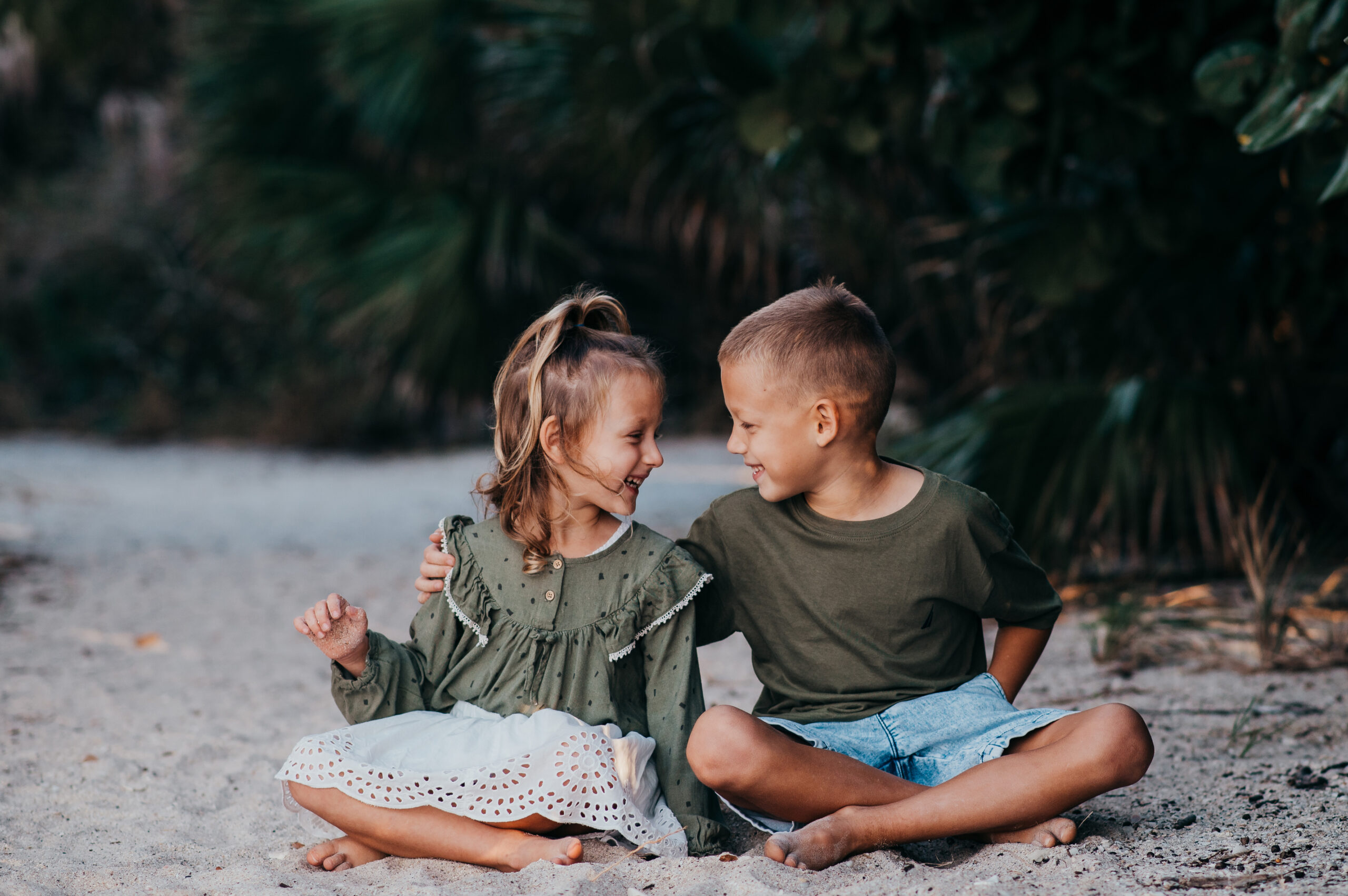 Beach portrait of sibling looking at each other and smilig