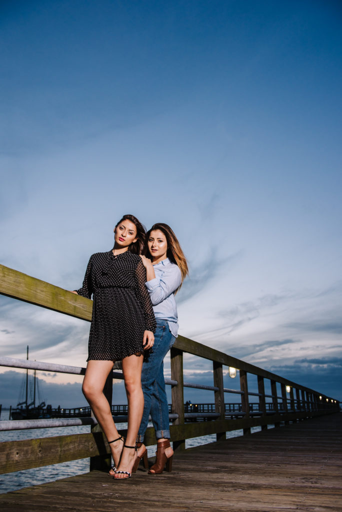 Two high school seniors posing on a pier at sunset.