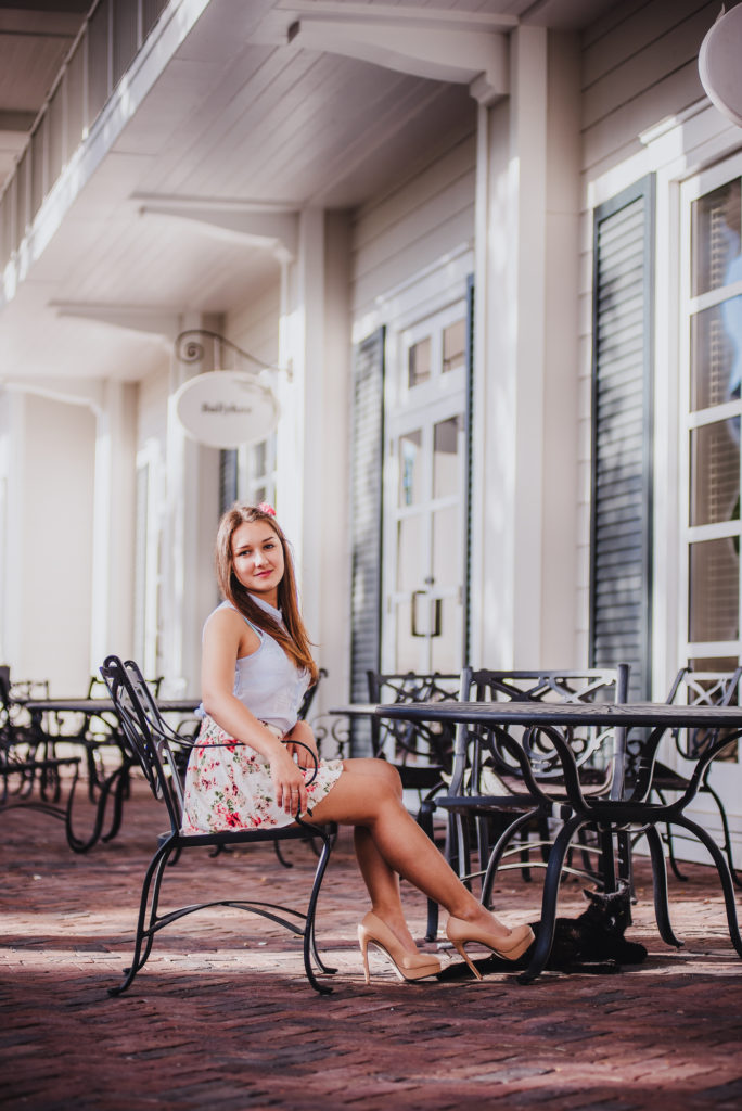 a senior portrait of dark hair girl sitting on a a chiar in coffee shop