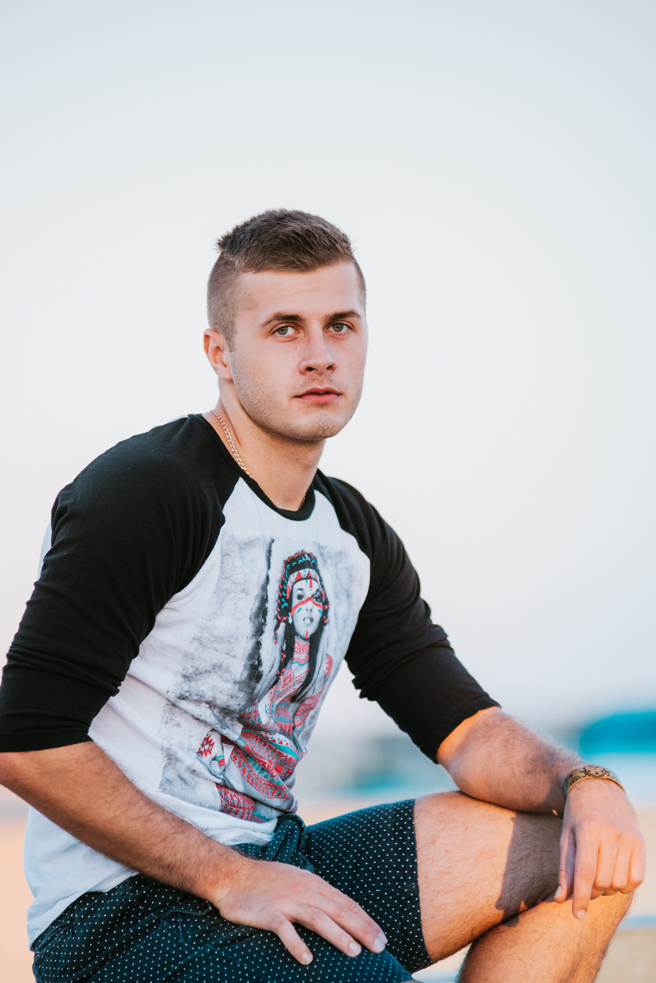 A young man sitting on a rock in front of the ocean.