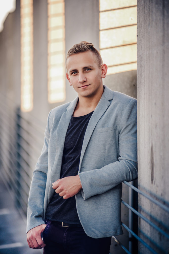 A young high school senior guy leaning against a wall at Sarasota downtown