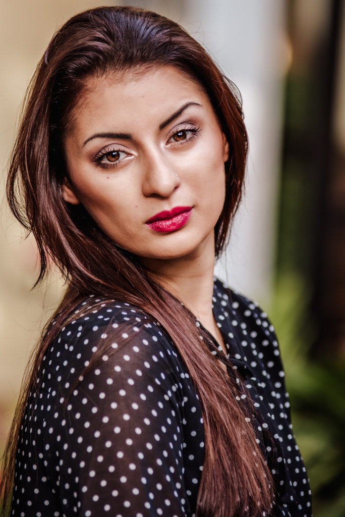 A close up of beautiful girl in a black and white polka dot top.