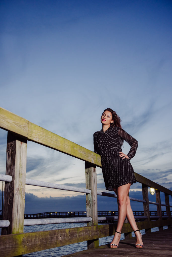 A night portrait of high school young woman posing on a wooden pier for her senior portraits