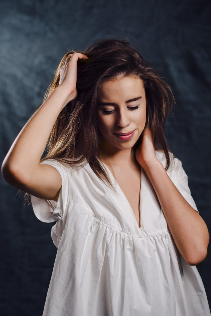 A young woman posing with her hands on her head at the studio portrait session