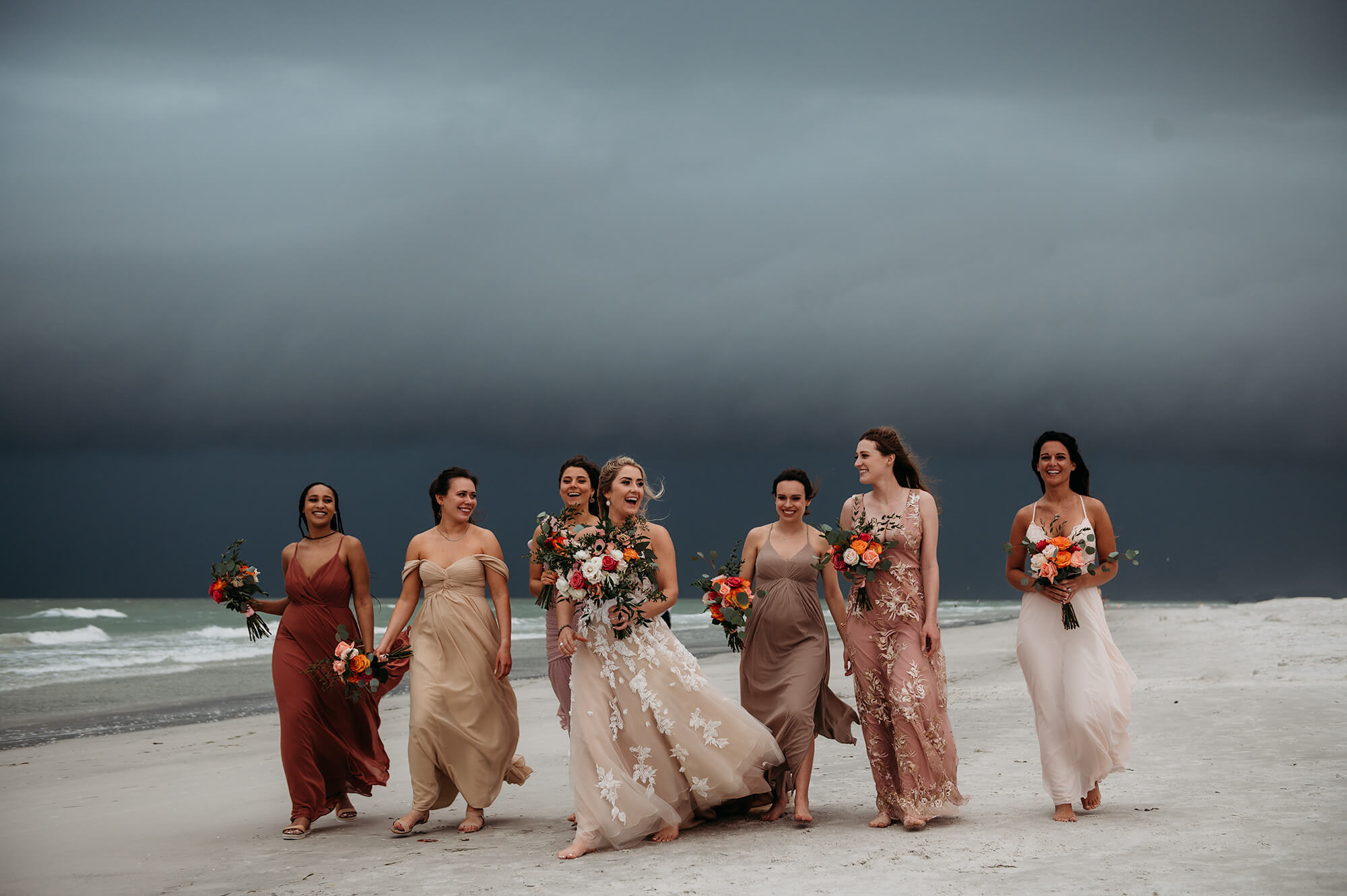 bride with bridesmaids walking at Siesta Key beach with stormy sky as a background