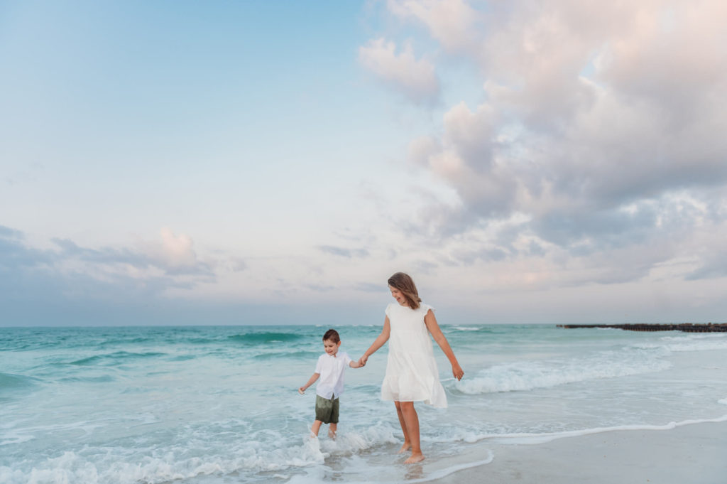 Candid image of brother and sister playing in the emerald color water during sunrise session