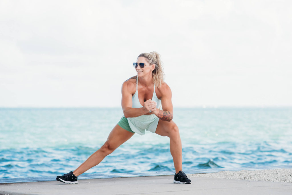 A fitness and health coach doing squats in front of the ocean during her personal branding photoshoot