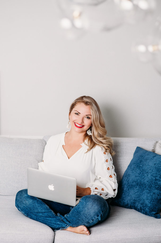 personal branding portrait of the blond women sitting on sofa with the laptop on her laps