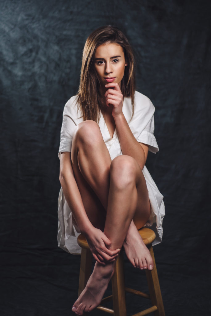 A sarasota photographer captures a modern portrait of young woman seated on a stool.