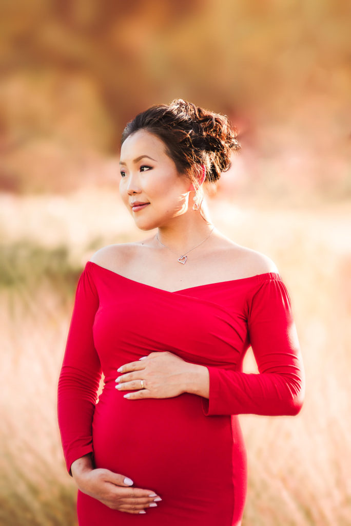 Close up maternity portrait of asian women in red dress looking away during a sunset session