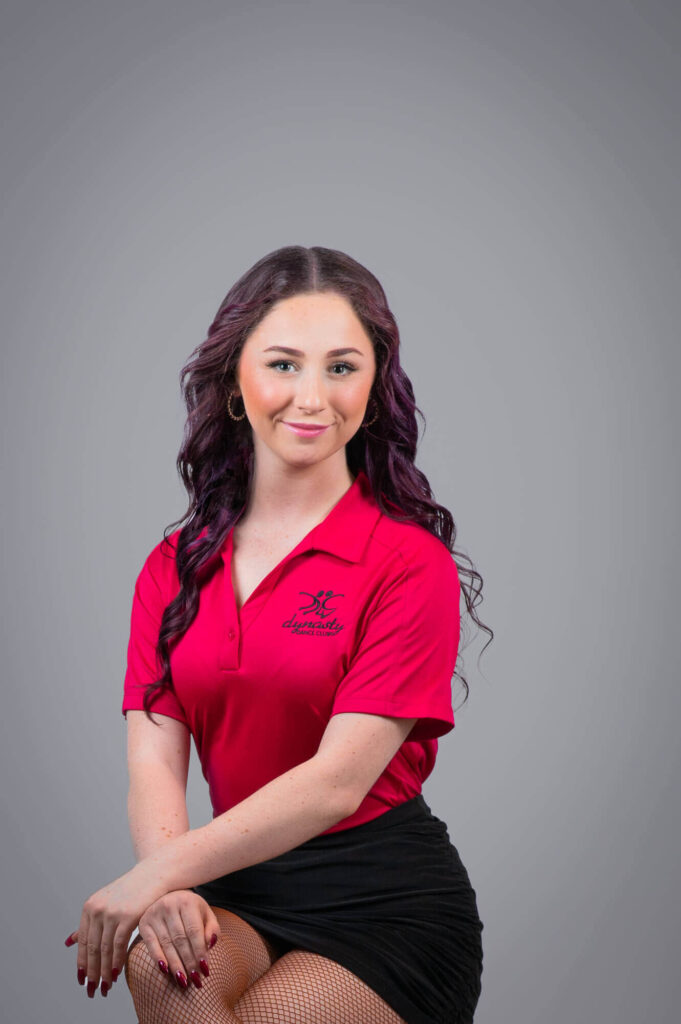 Commercial headshot of dance instructor wearing magenta company shirt with logo
