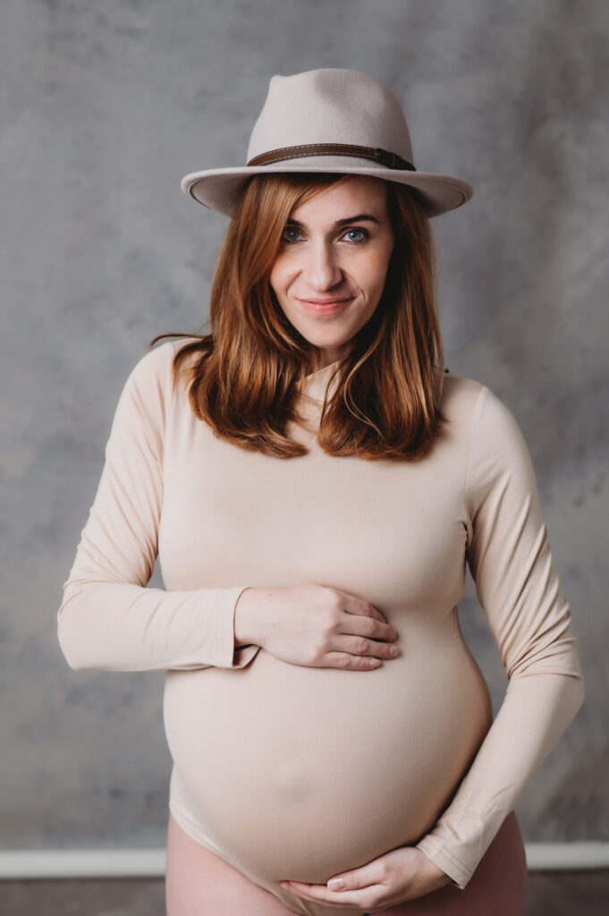 A pregnant woman in a hat poses for a photoat Sarasota Portrait studio