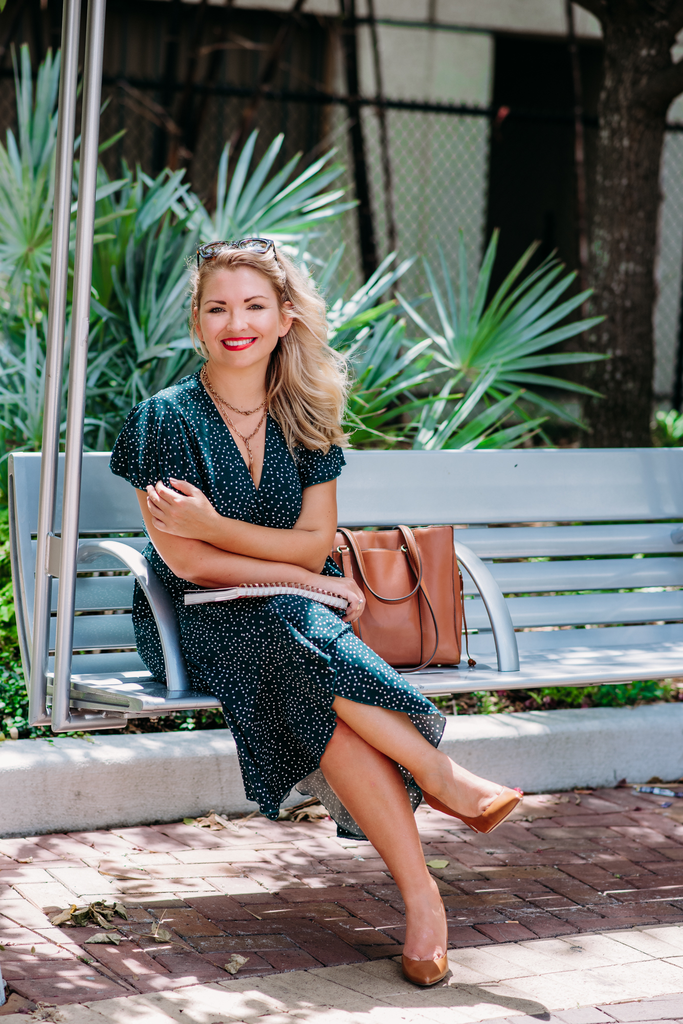 A life coach sitting on a bench in her personal brand photoshoot, confidently donning a stylish green polka dot dress.