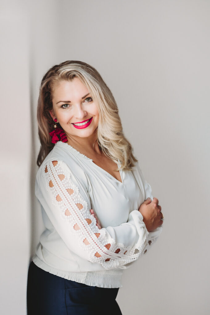  Professional portrait of beautiful blond women with red lipstick leaning on the wall