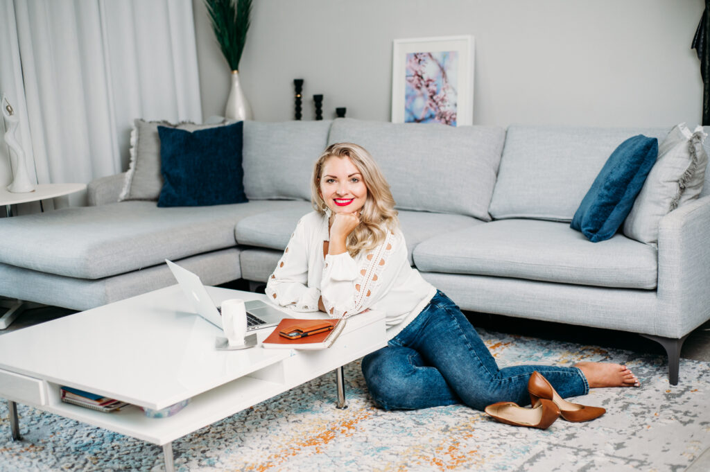 A woman sitting on the floor during a personal brand photoshoot, working with her laptop.