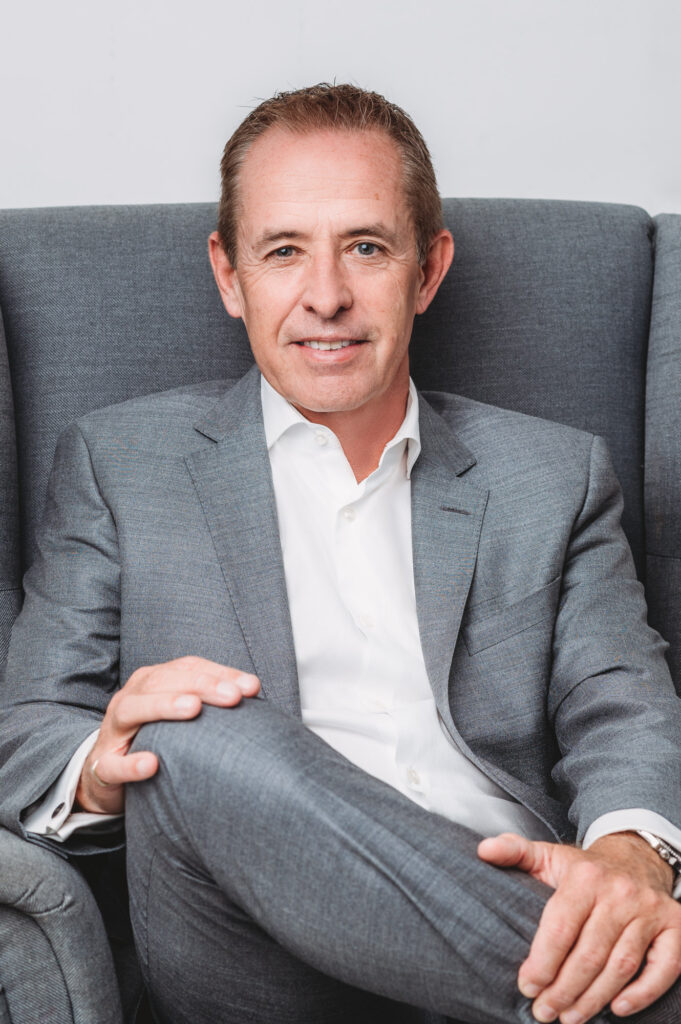 modern headshot of a man siting in comfortable position in his grey suit