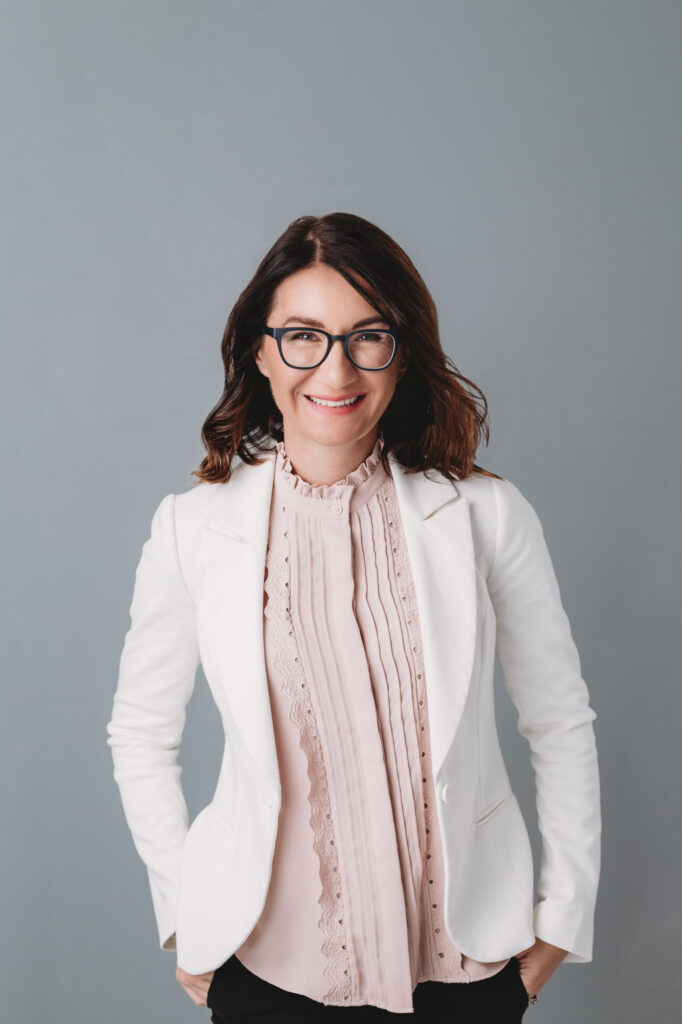 Modern studio portrait of women in pink shirt and white jacket smiling in to camera