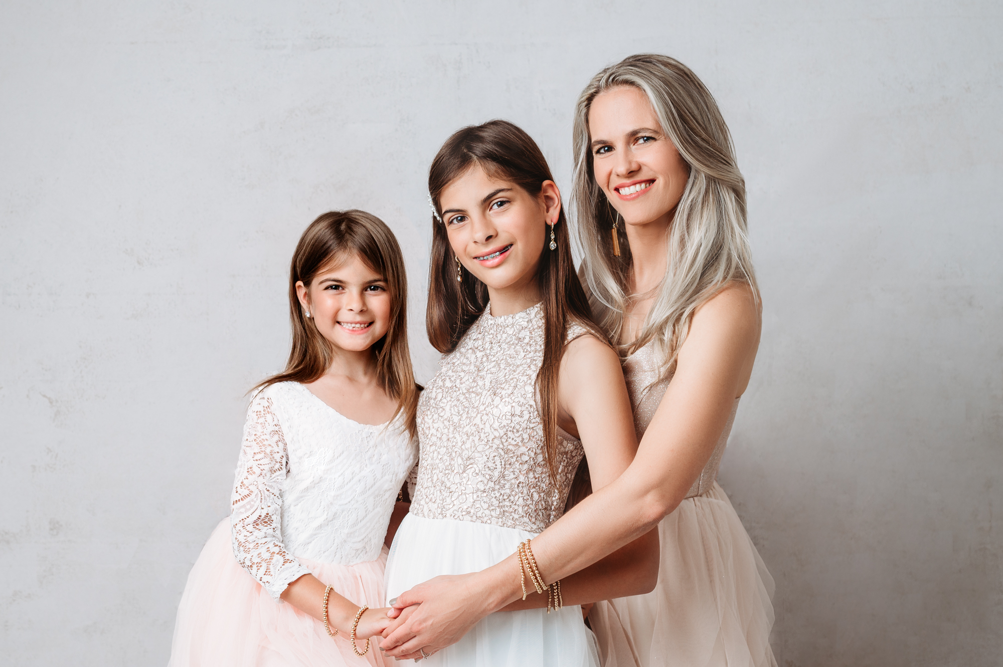 beautiful portrait of mom with two daughters in blush dresses posing for a photo.