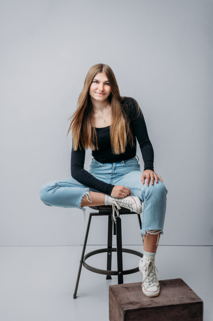 A young woman posing at a portrait studio for her senior portrait