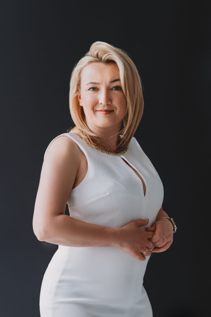 A professional woman in a white dress posing for a business portrait.