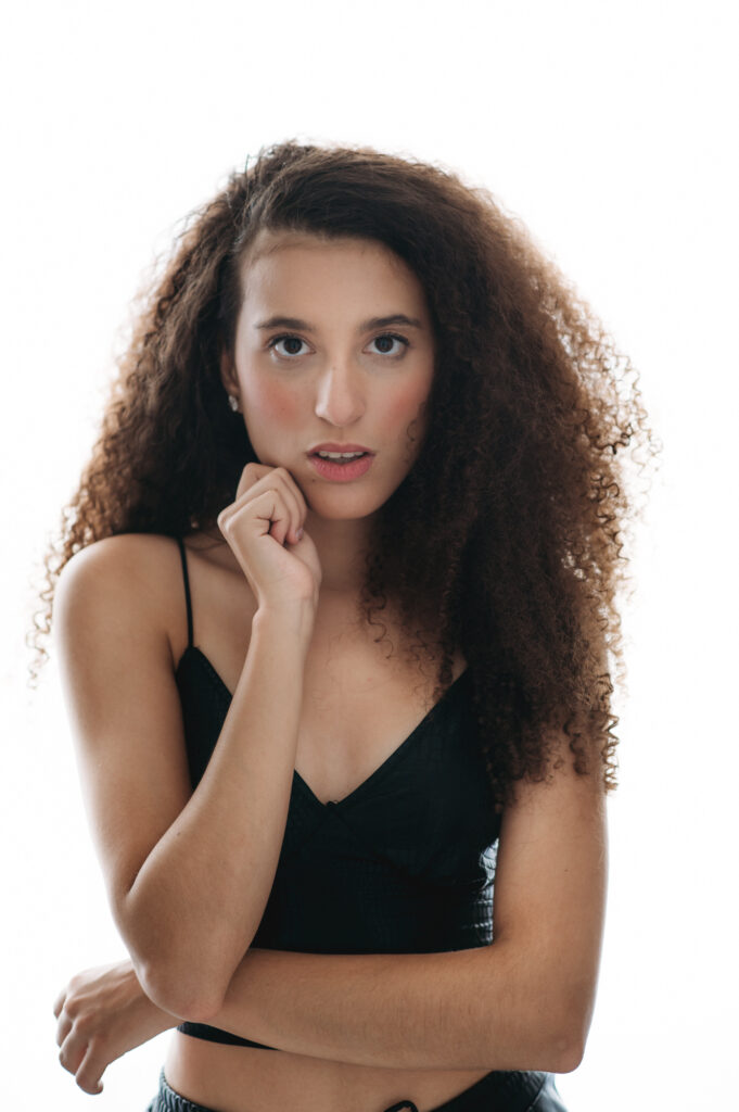 A young woman with curly hair posing fon the bright white background