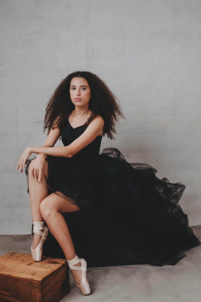 A young woman in a black ballet dress posing on a box in Sarasota Portait studio