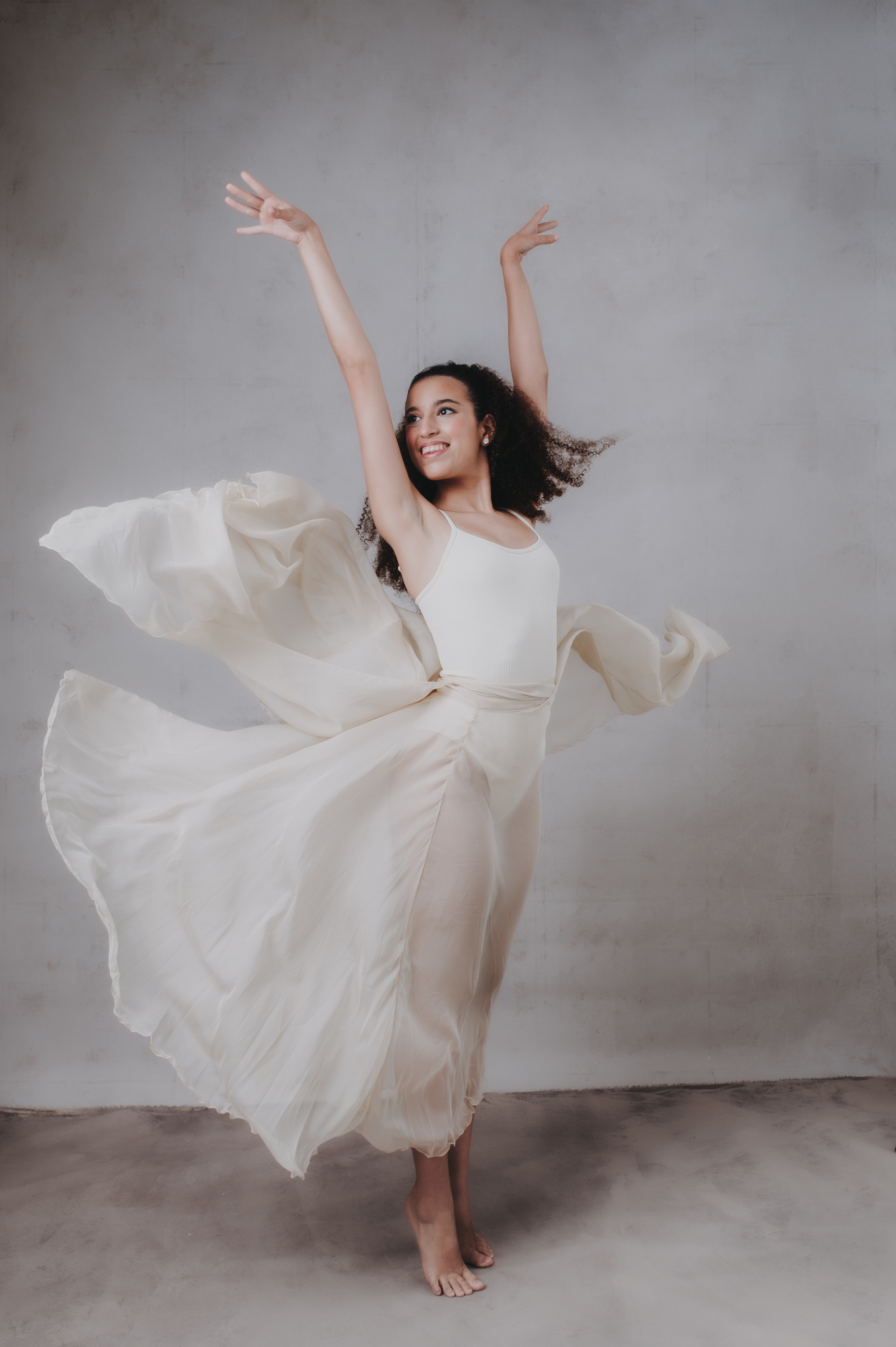 a dance passion high school senior girl portrait on a gray background at Sarasota studio with flowing dress