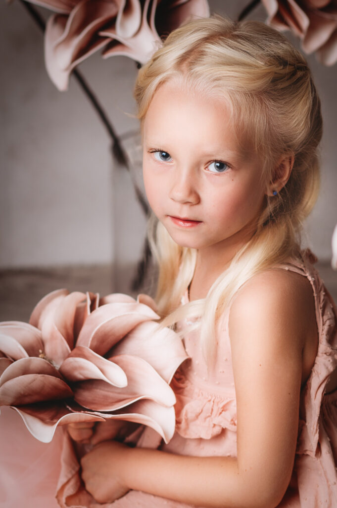 A sarasota photographer captures a little girl in a pink dress holding flowers.