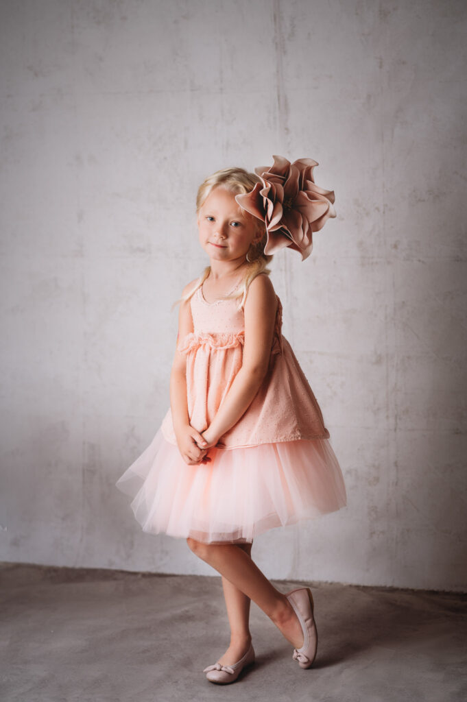 A little girl in a pink dress posing for a photo by a Sarasota photographer.