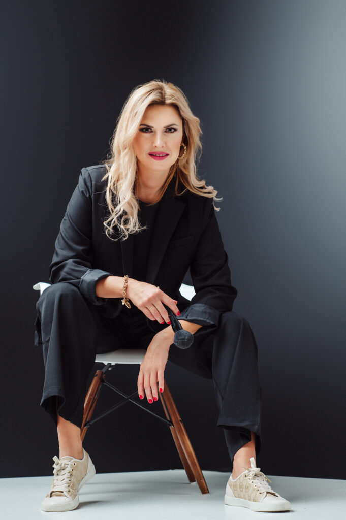 A woman in a black suit sitting on a chair during a Sarasota personal branding photography session.