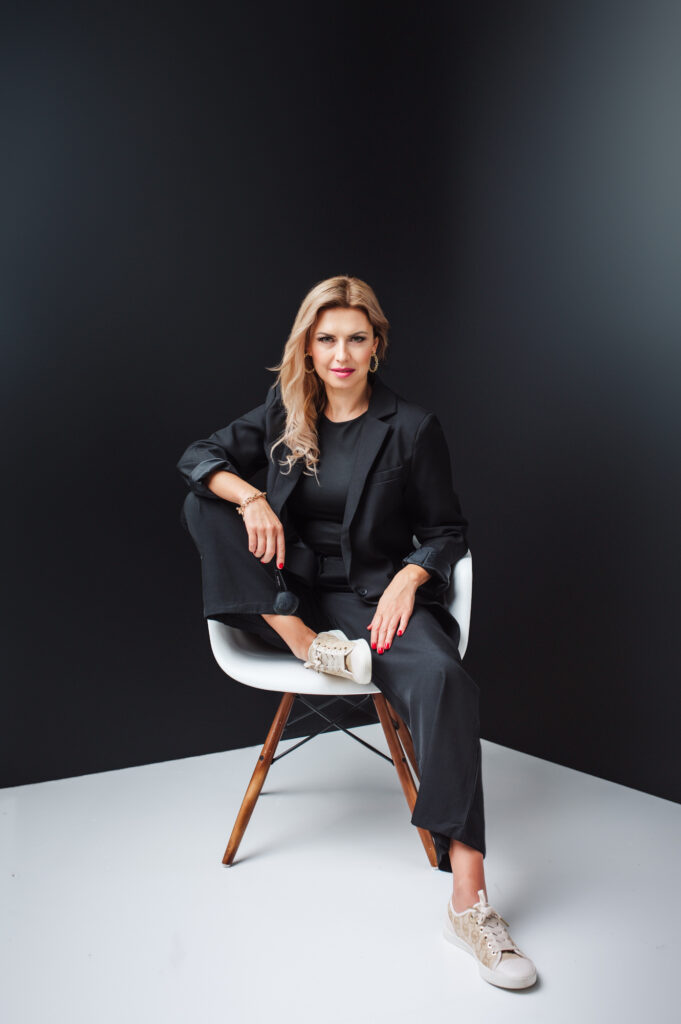 A woman in a black suit sitting on a chair, captured beautifully in Sarasota personal branding photography.