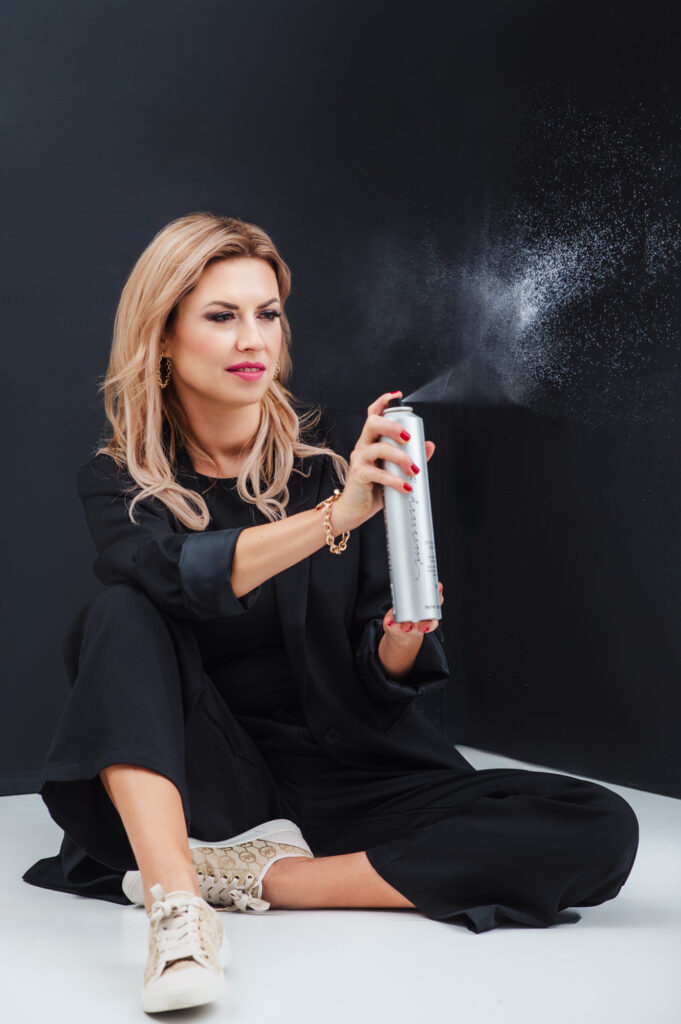 A woman using a spray can for Sarasota personal branding photography on a black background.