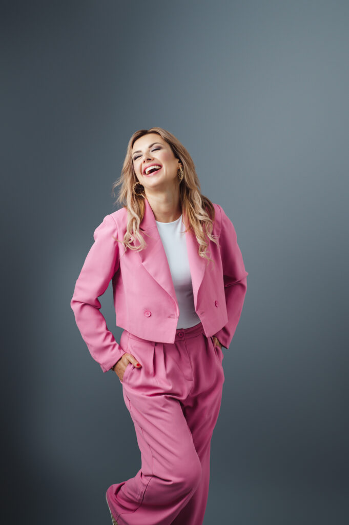 Sarasota personal branding photography of a woman in a pink suit posing on a gray background.