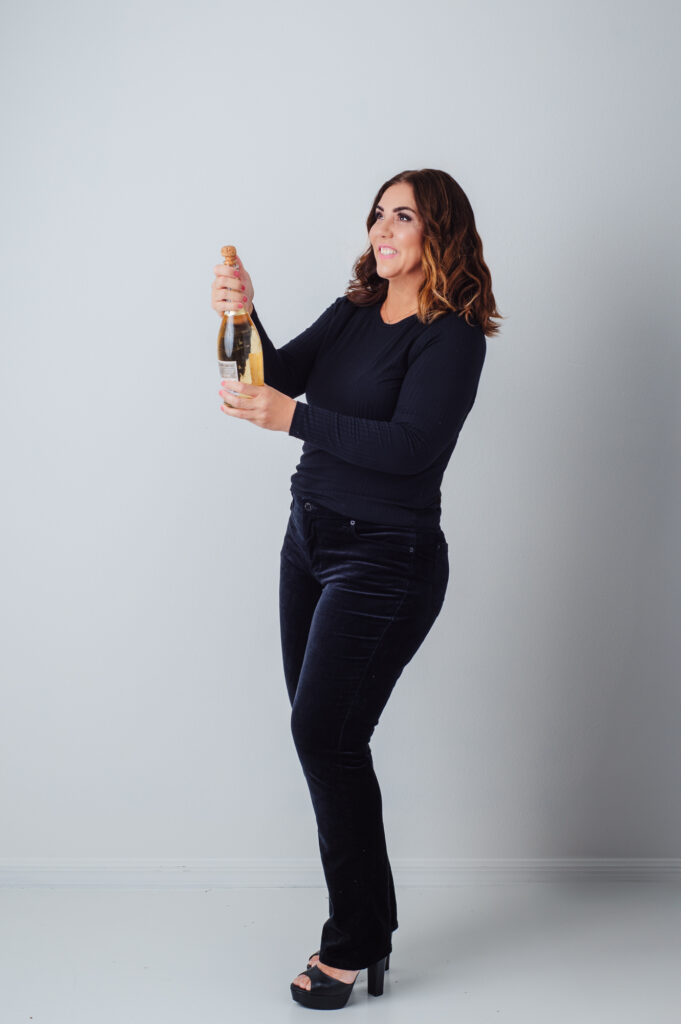 A woman showcasing Sarasota personal branding photography with a bottle of champagne in hand.