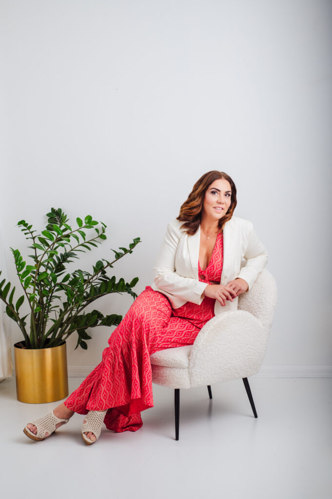 A woman in a red dress sitting on a chair, captured beautifully by Sarasota personal branding photography.