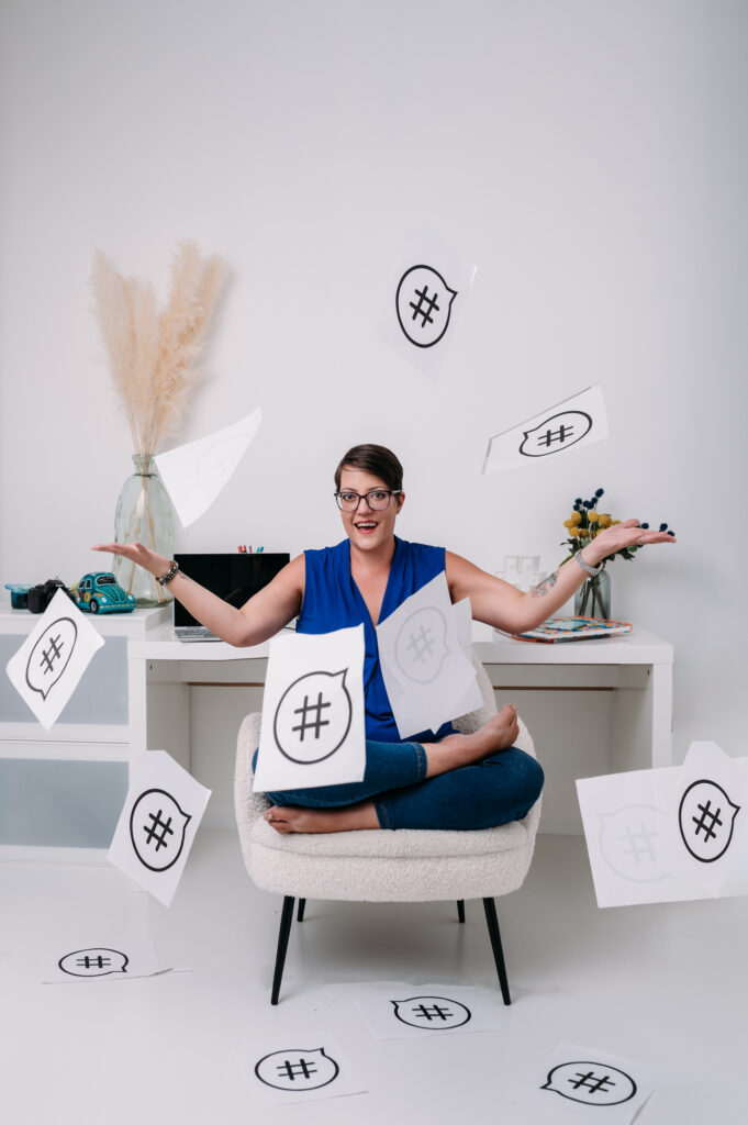 A woman sitting on a chair with a flurry of paper flying around her, captured in striking personal branding photography.