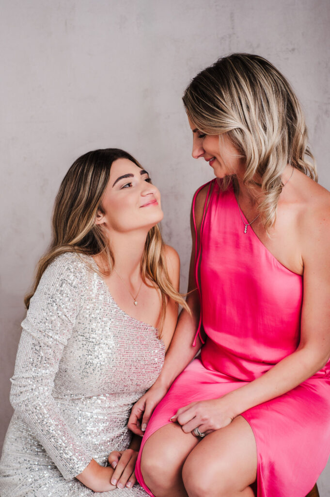 Mother and daughter portrait looking at each other with a smile wearing beautiful elegant dersses