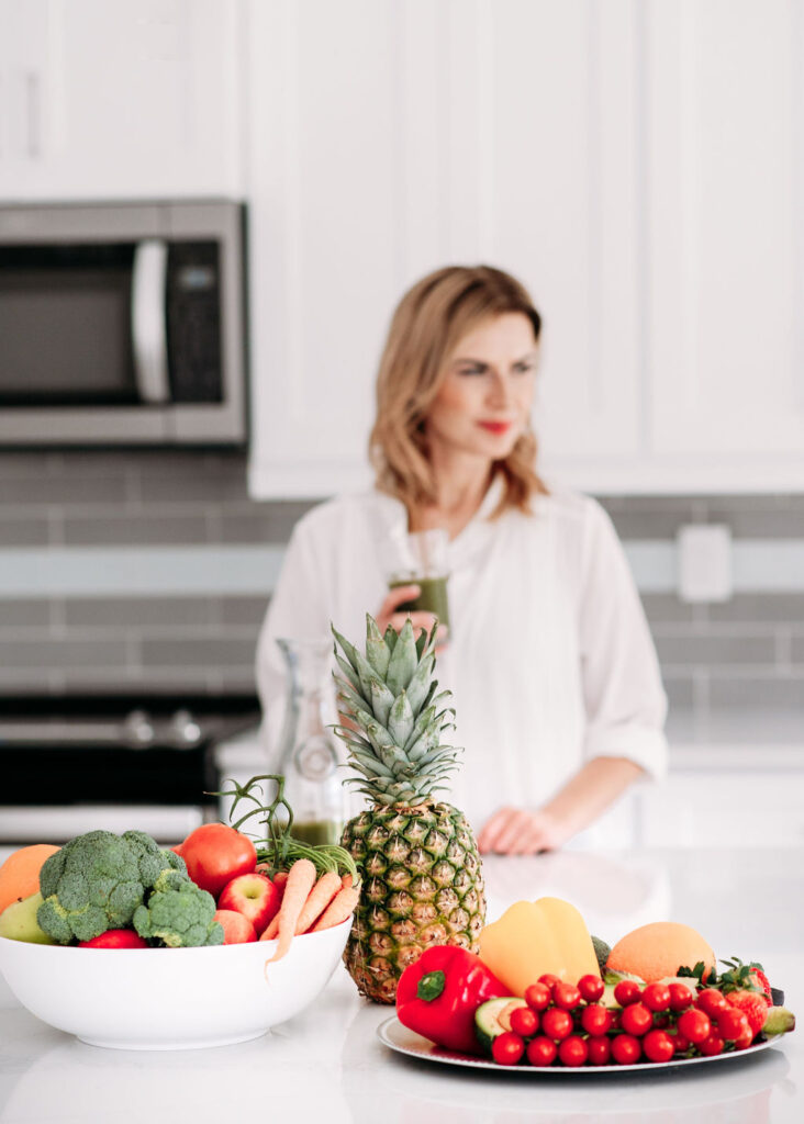 Picture of fruit and veggie with a women drinking green juice on the background