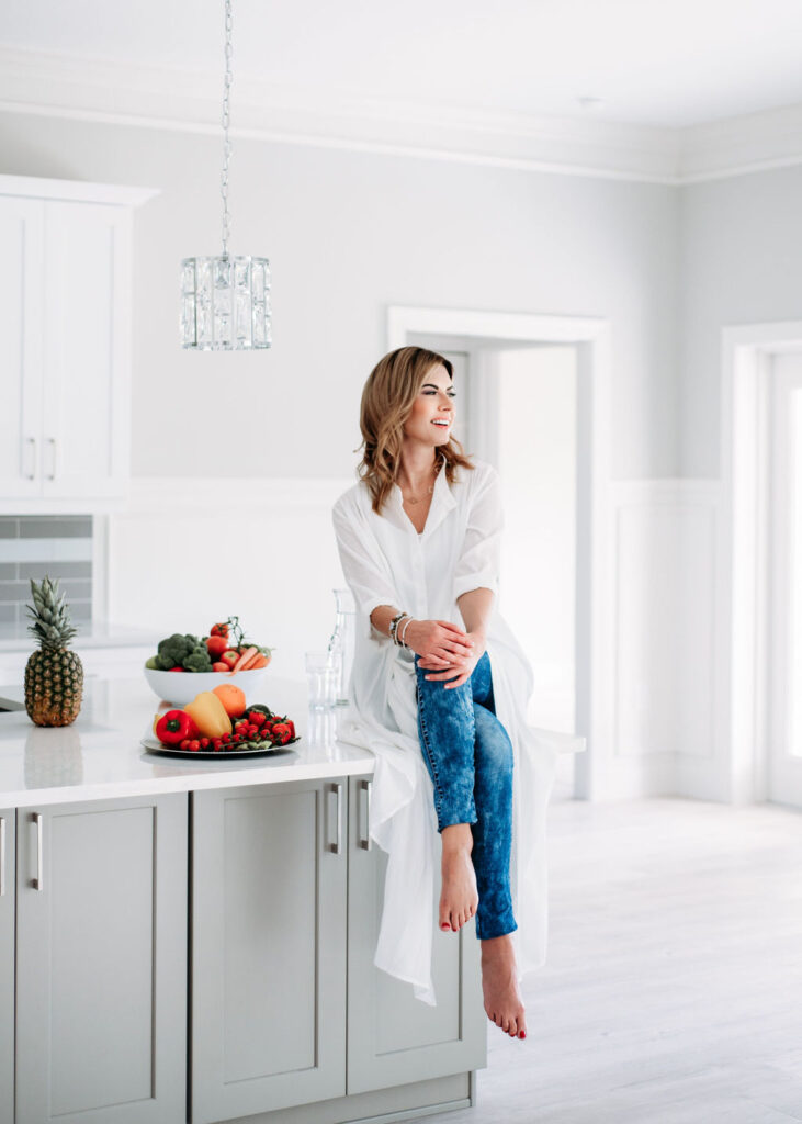 Lifestyle portrait of Health coach siting on the countertop kitchen looking at the outside