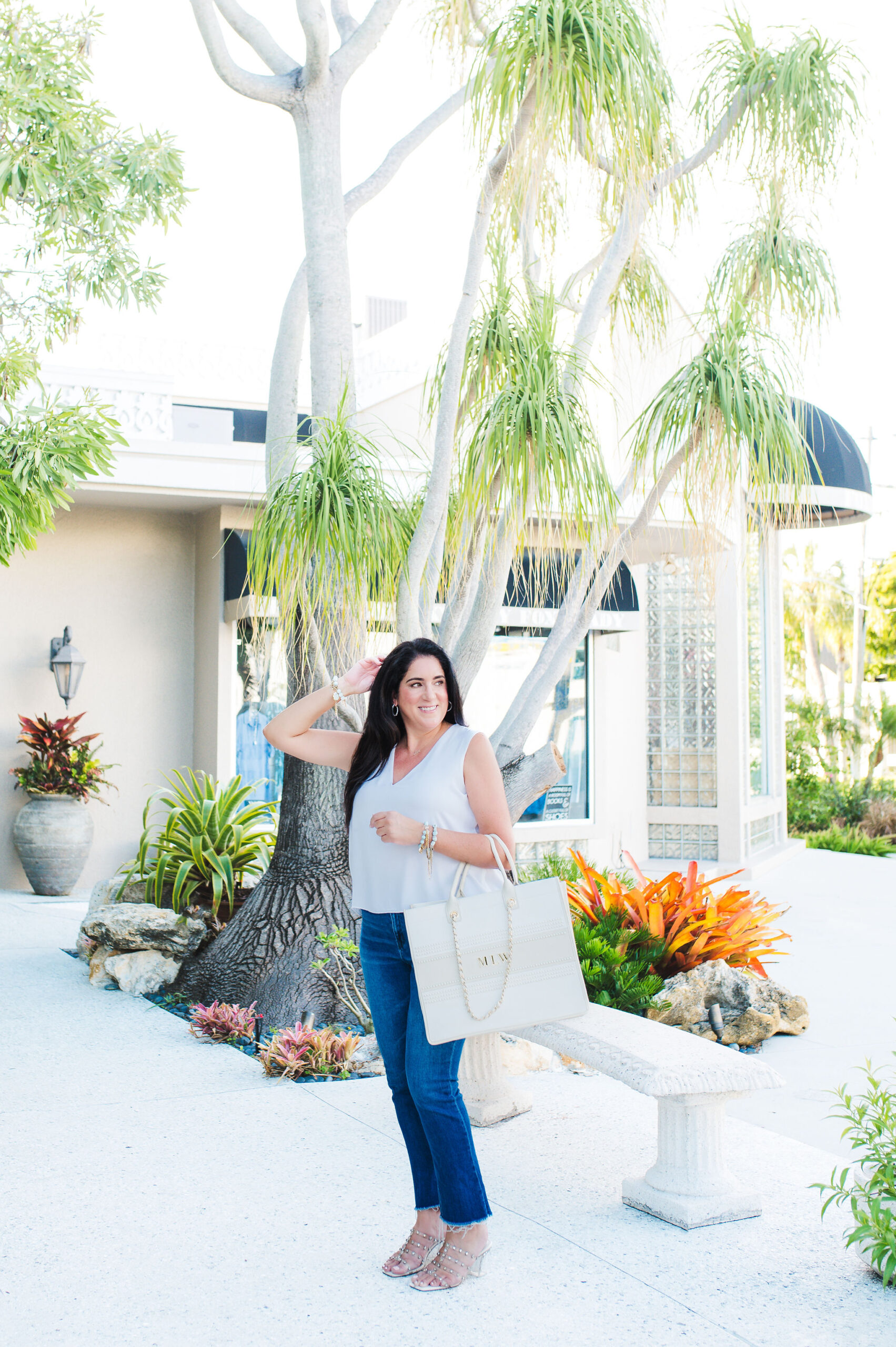 Brand photo of women wearing whit top and blue jeans with big purse at St Armands  Circle in Sarasota