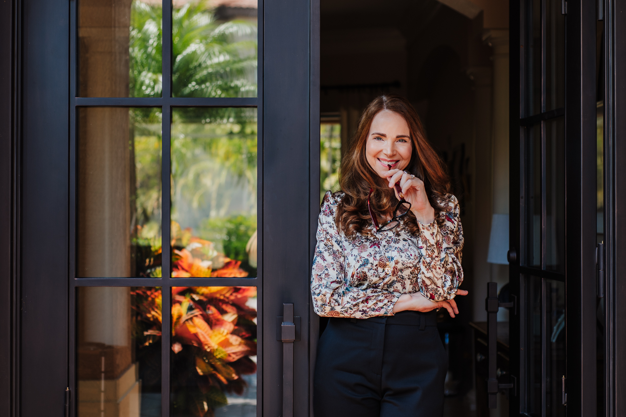 Beautiful women standing in the door with glasses in her hand posing for brand image for her coaching business