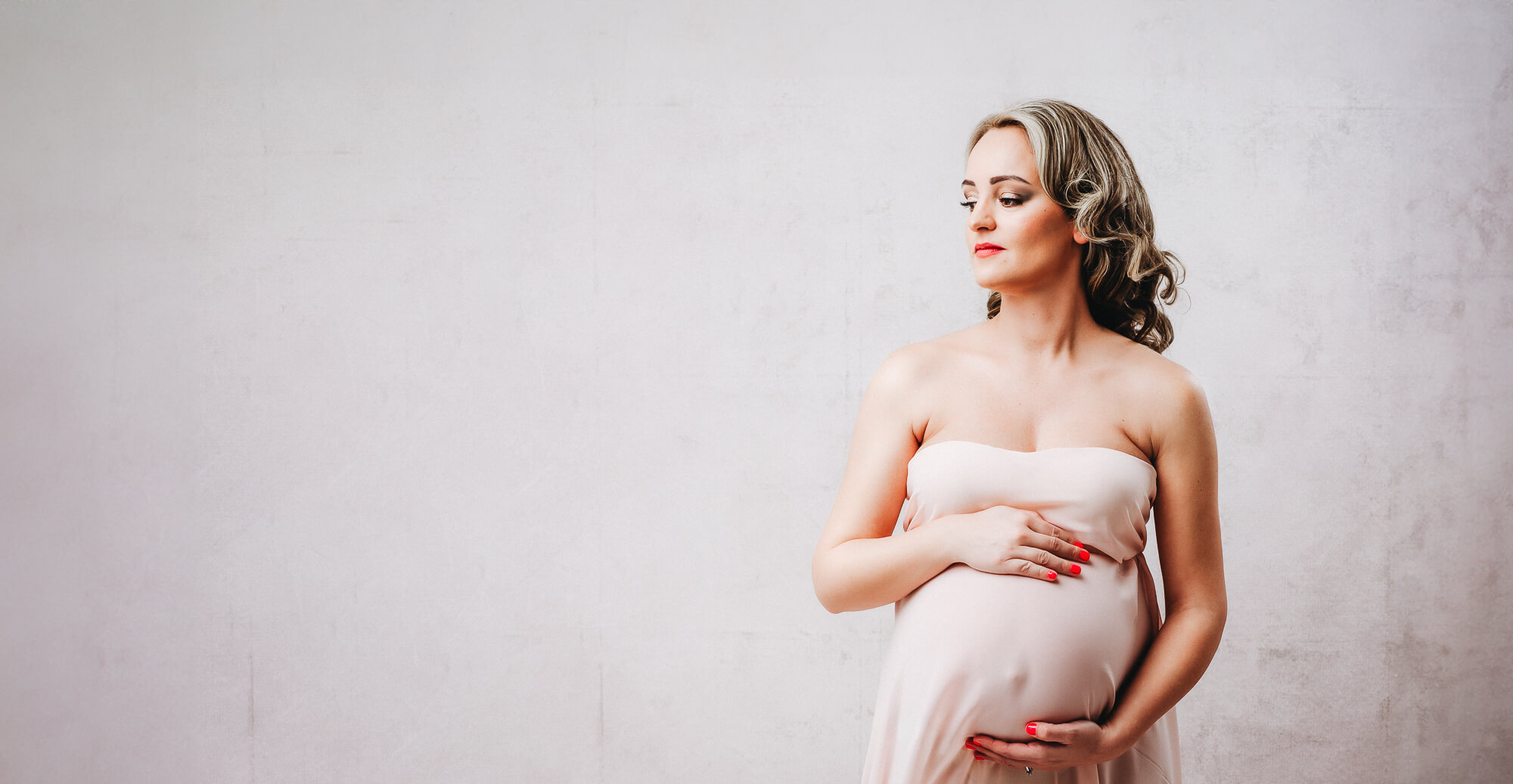 beautiful studio portrait of pregnant women wearing peach dress