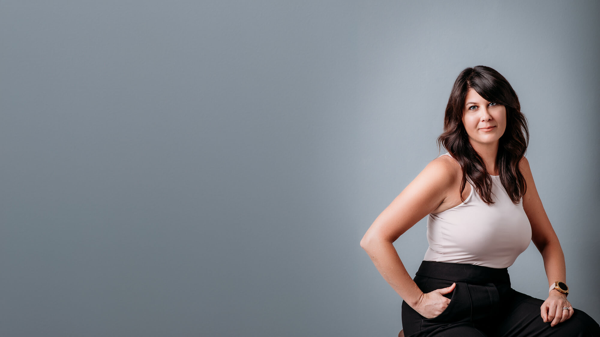 Modern headshot of dark hair women on grey background wearing tan shirt